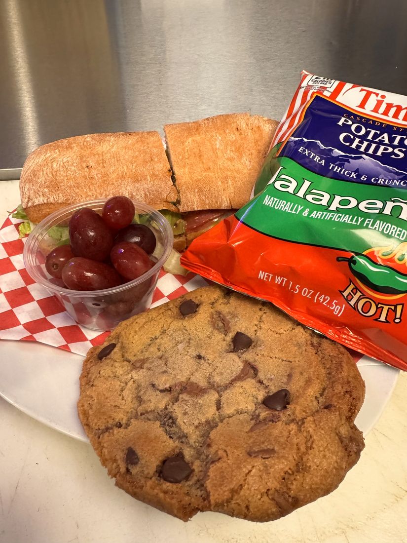 A boxed lunch with a sandwich, chips and a cookie