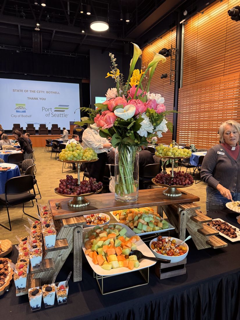 A catered breakfast table with fresh flowers and tiered platters