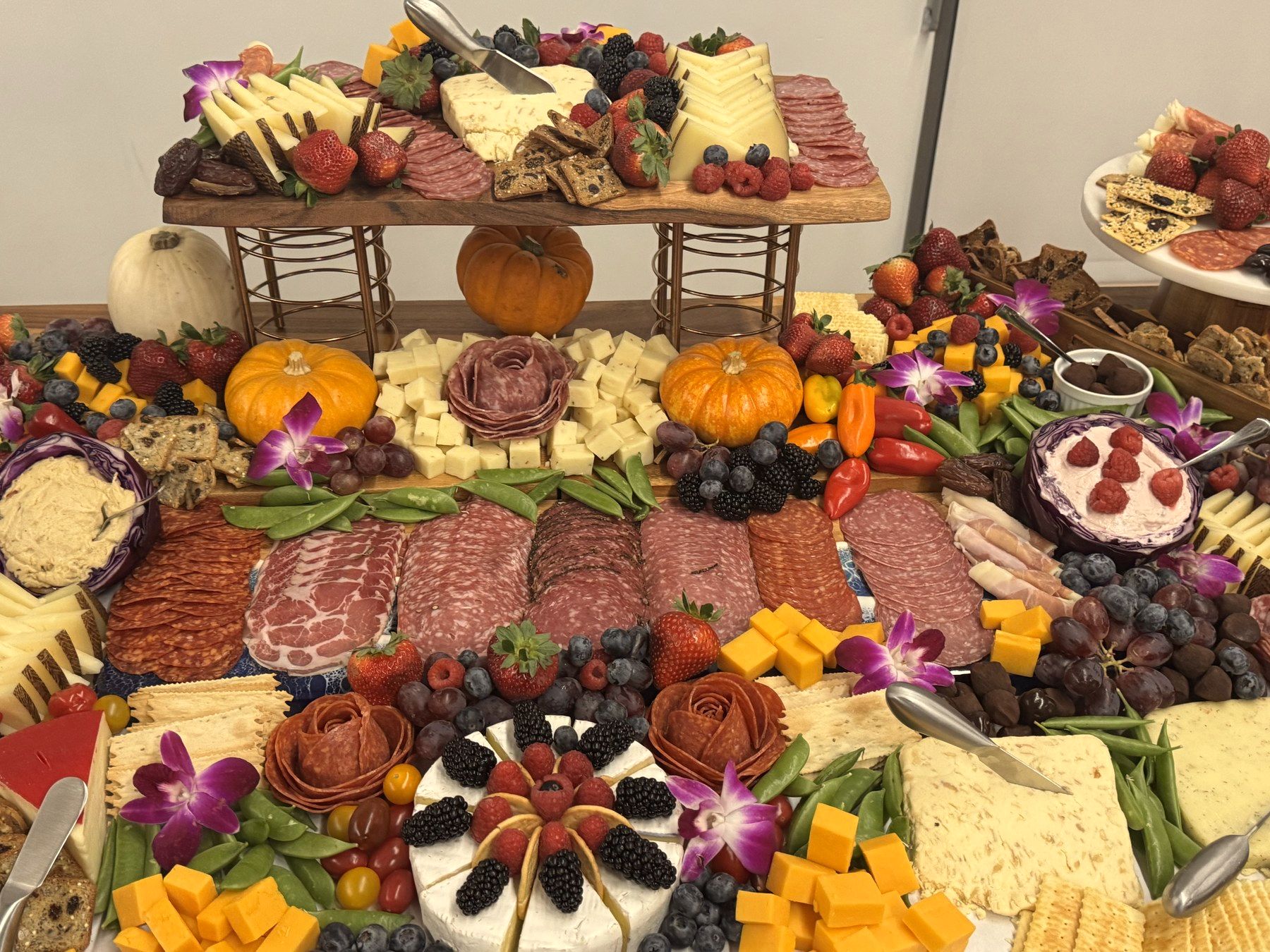 A long grazing table with charcuterie, cheeses, fruit and flowers